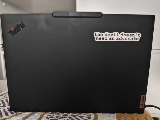 Photo of my laptop's back with a prominent sticker on it saying: "the devil doesn't need an advocate"