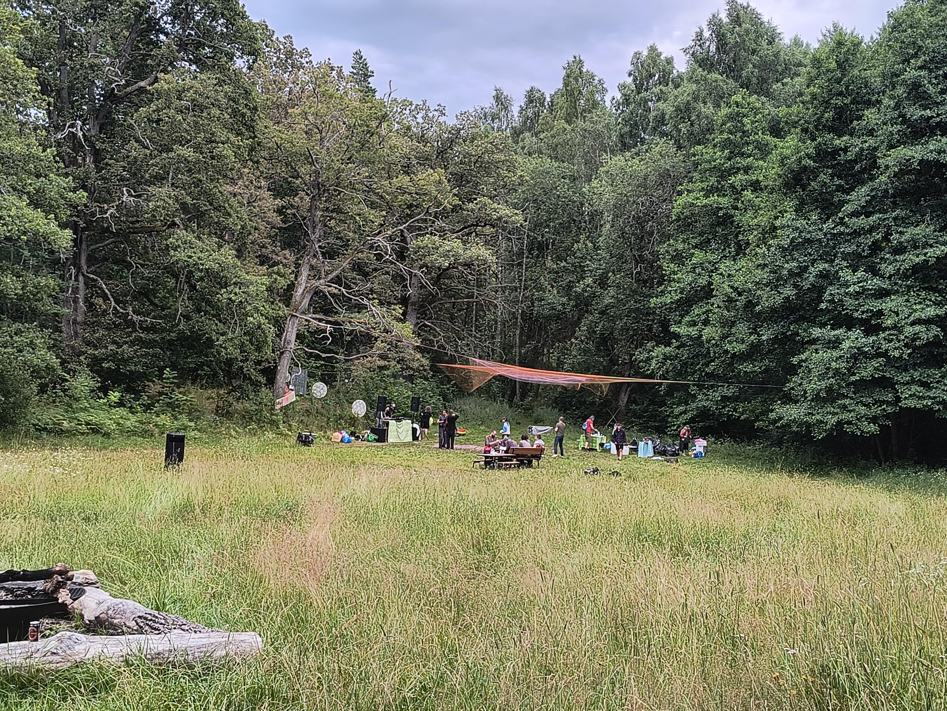The same place in the morning, from a bit of a distance, a few people left, probably cleaning up but still also dancing a bit, soundsystem still playing.